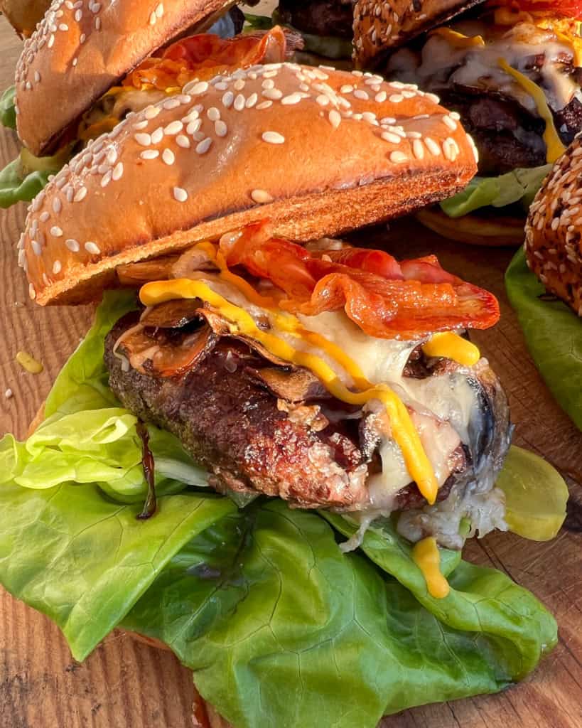 A loaded mushroom, Pancetta and Asiago Burger with lettuce on a sesame seed bun.