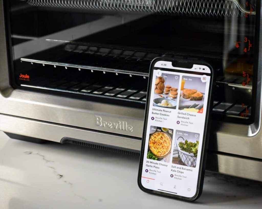 A close up of an iPhone leaning on a air fryer.