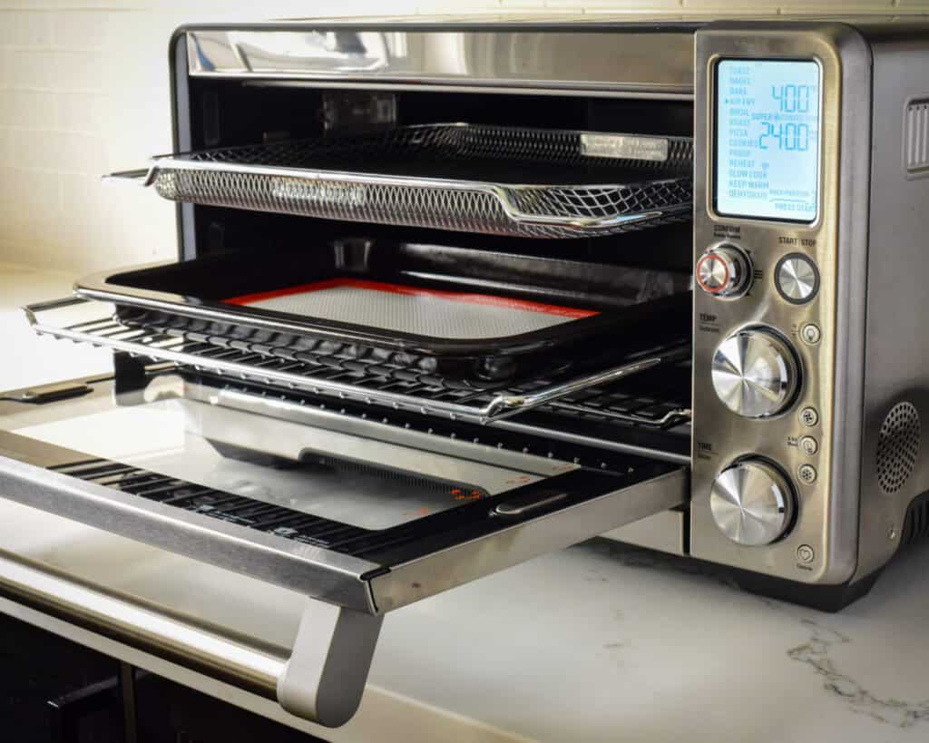 An air fryer with the doors open revealing the shelves and accessories that come with it.