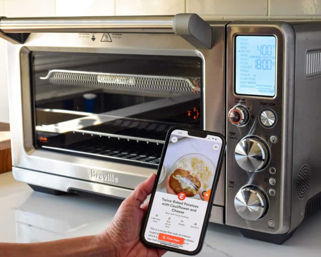 A close up of an air fryer and an iPhone with the recipe app ready to start.
