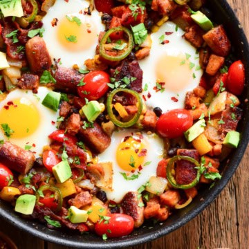 A skillet of hash browns and eggs with other vegetables.