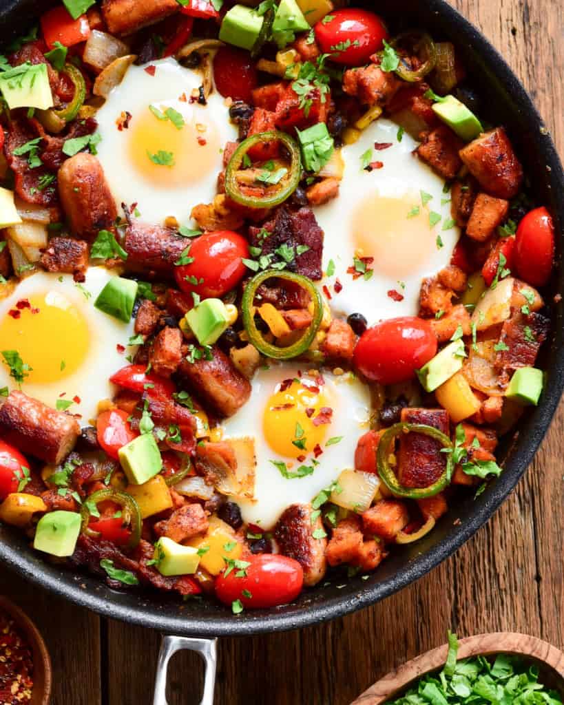 A skillet of hash browns and eggs with other vegetables.