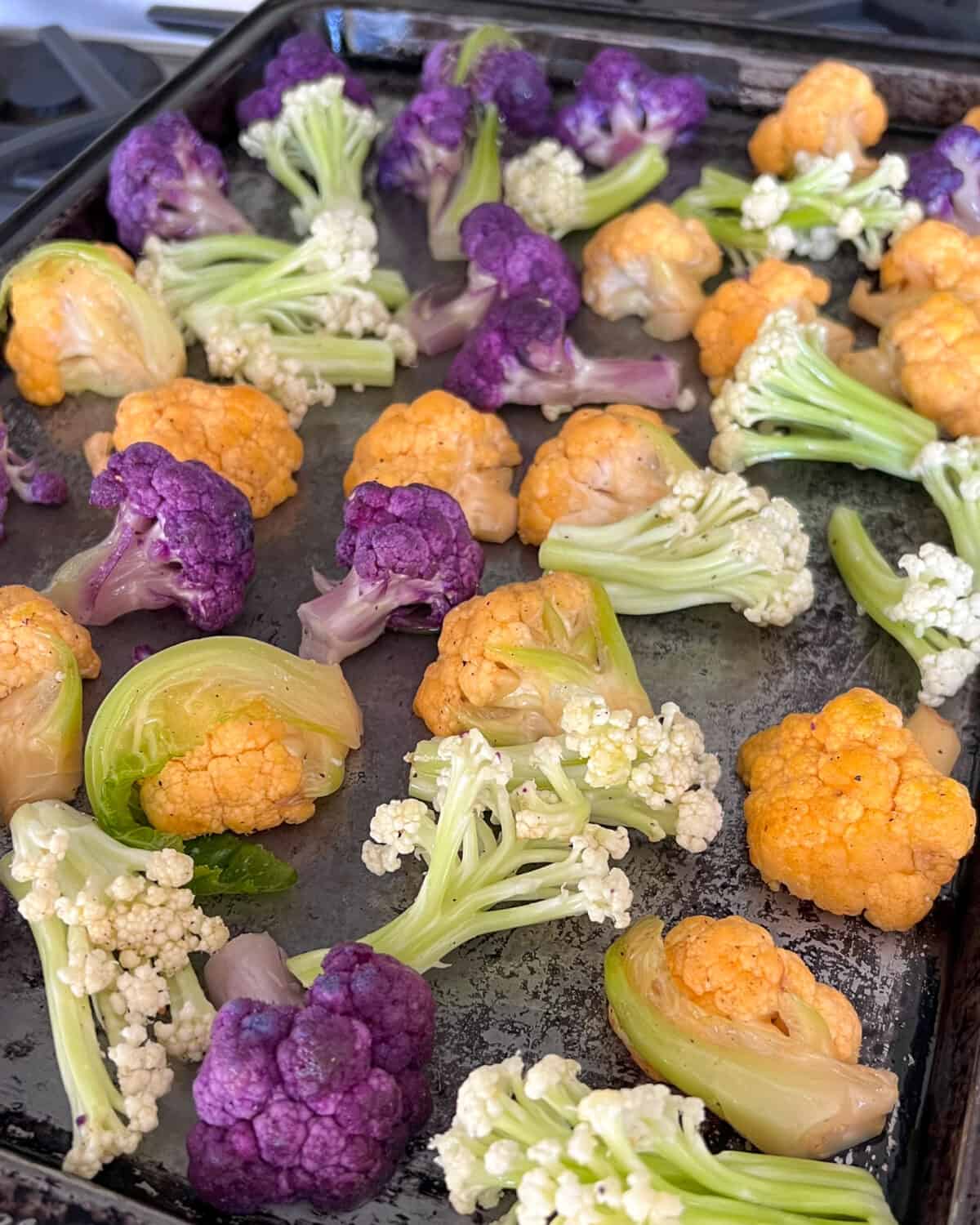 Three types of cauliflower on a sheet pan about to get roasted.