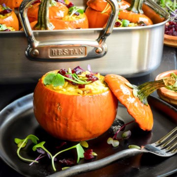 A Mini Stuffed Pumpkin with Wild Rice in front of a roasting pan.