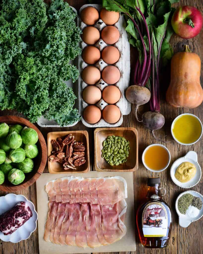 Ingredients laid out to make a Fall Harvest Salad with Apple Cider Vinaigrette with eggs and fall produce.