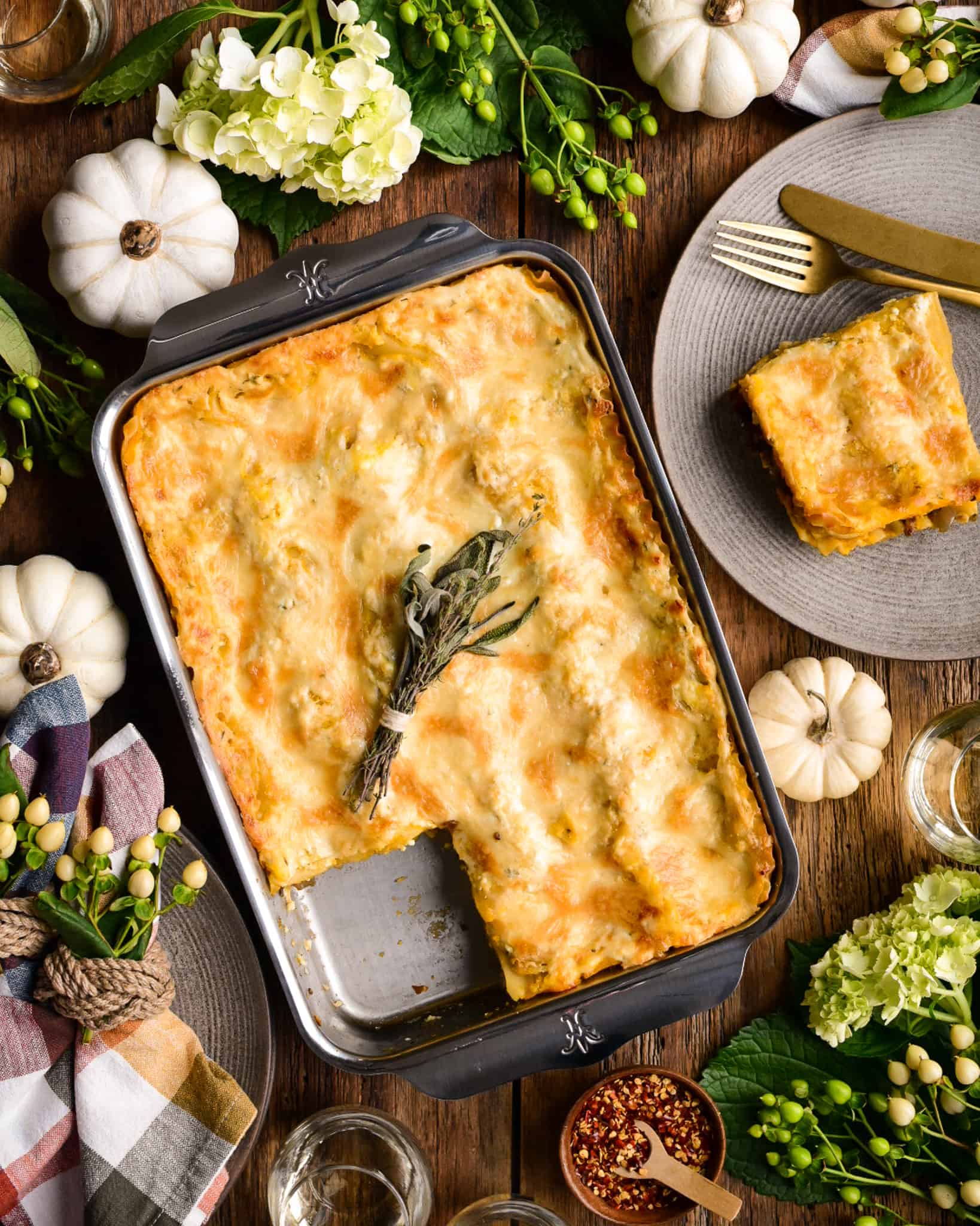 A baking dish with a piece of lasagna on the plate beside it.