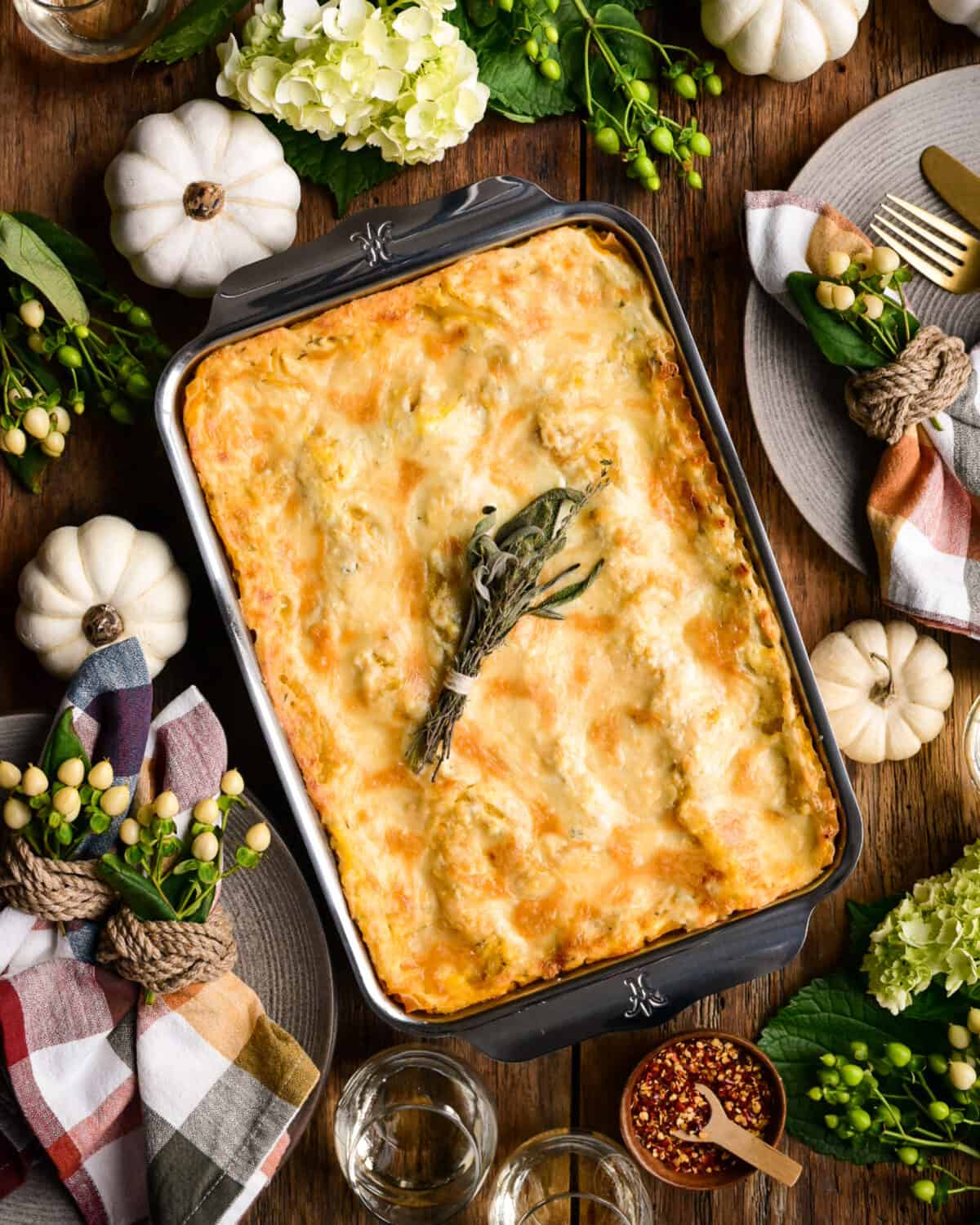 A baking dish with a fall lasagna, on a fall table setting.