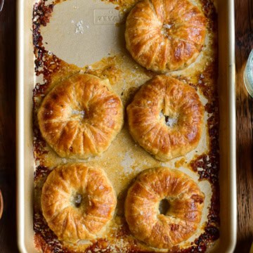 A close up of five donut-like apple pies on a tray.