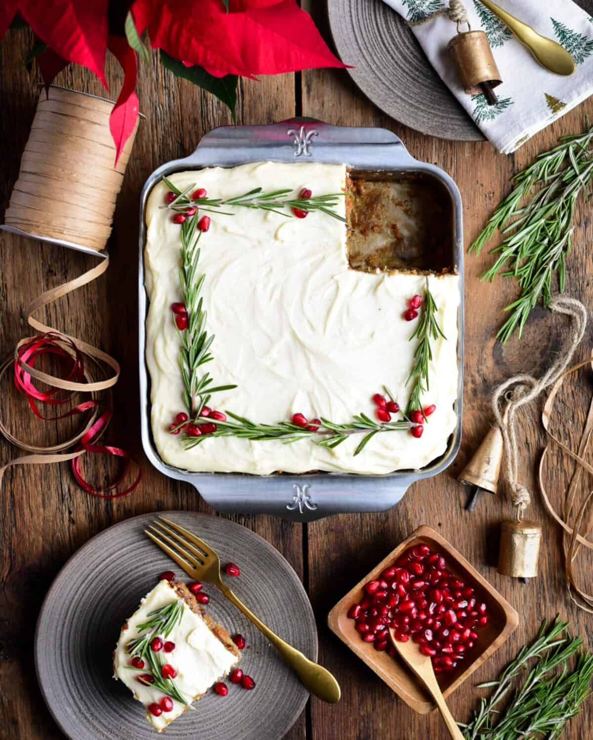 An 8x8 pan with festively decorated carrot cake with a piece missing and on a plate.
