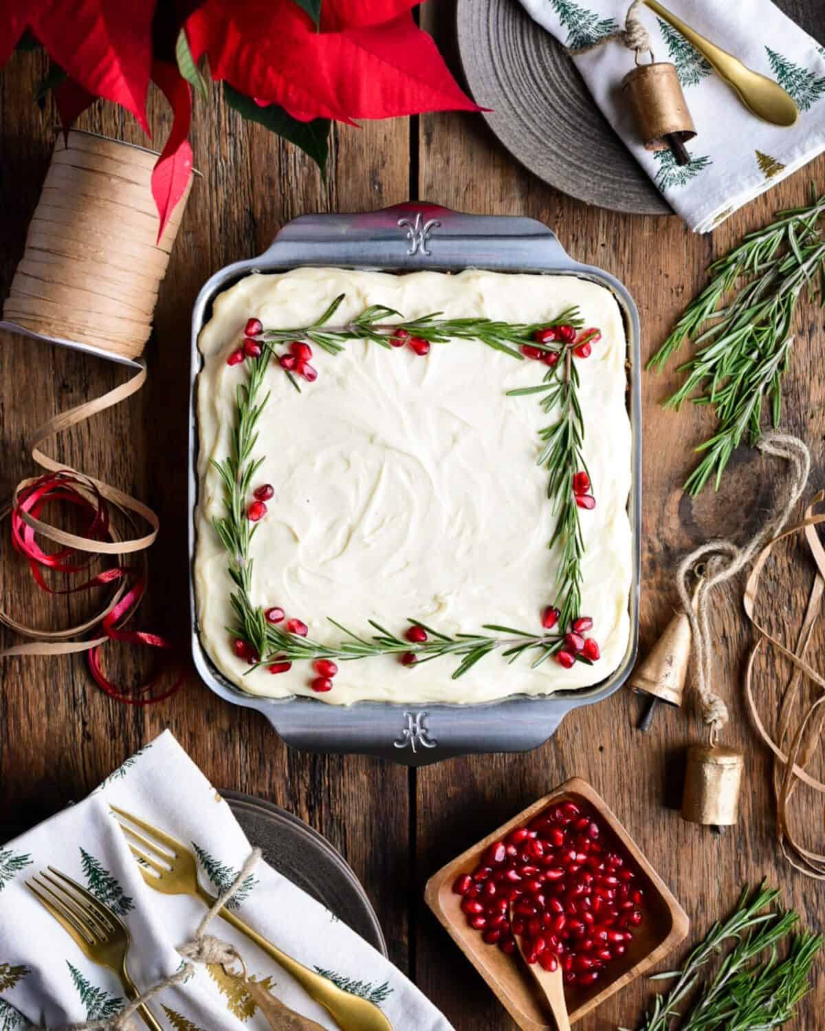 A top down view of a Christmas Carrot cake decorated with pomegranate arils and rosemary.