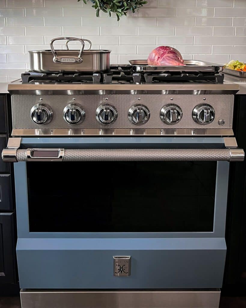 A roaster and sheet pan with a lamb on it sitting on a light blue range.