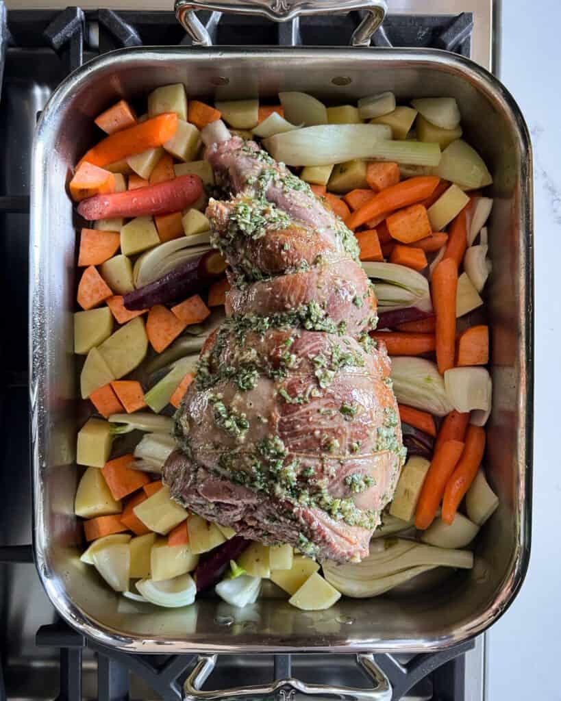 A rosemary lamb roast on mixed root vegetables ready to go into the oven.