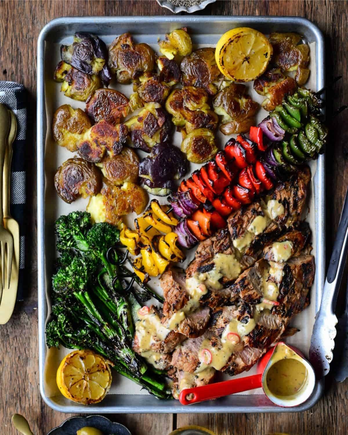 A colourful platter of Spicy Maple Pork Tenderloins, skewered vegetables, smashed potatoes and broccolini.