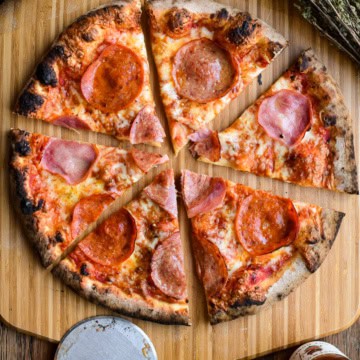 A sliced meat lover's pizza on a pizza peel.