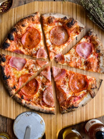 A sliced meat lover's pizza on a pizza peel.