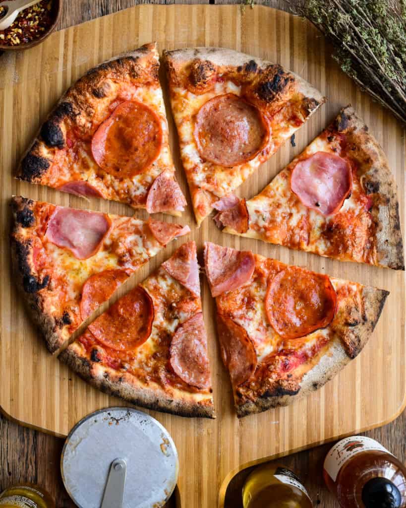 A sliced meat lover's pizza on a pizza peel.