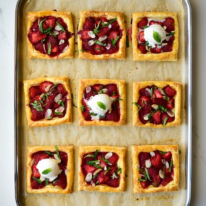 Nine Puff Pastry Strawberry Tarts on a sheet pan, served with a scoop of ice cream.