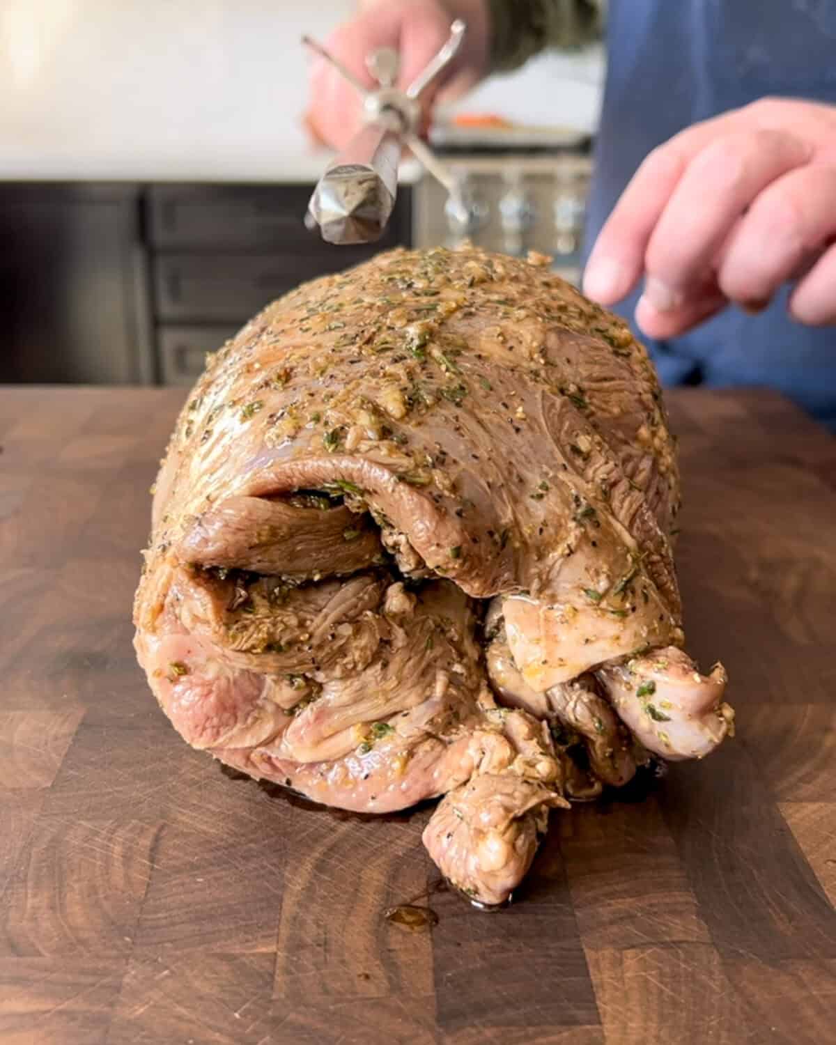 Slide the spit of the rotisserie through the center of the lamb.
