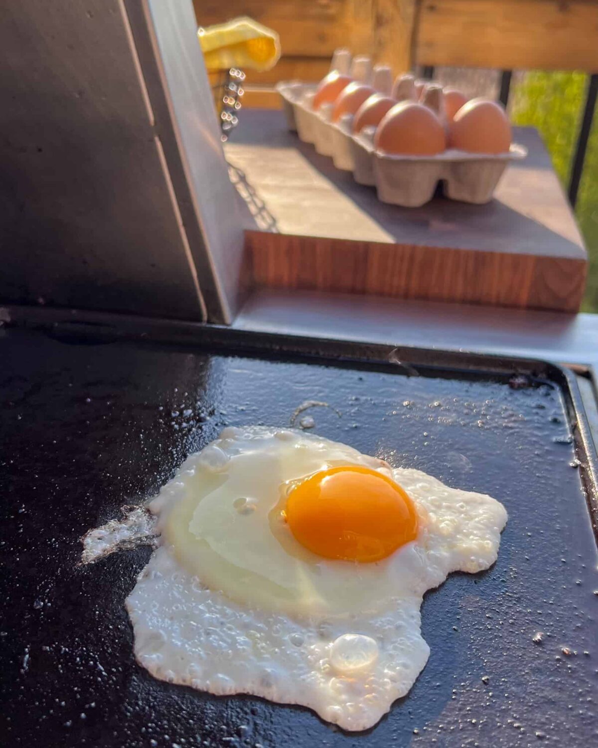 A fried egg on a griddle outside.