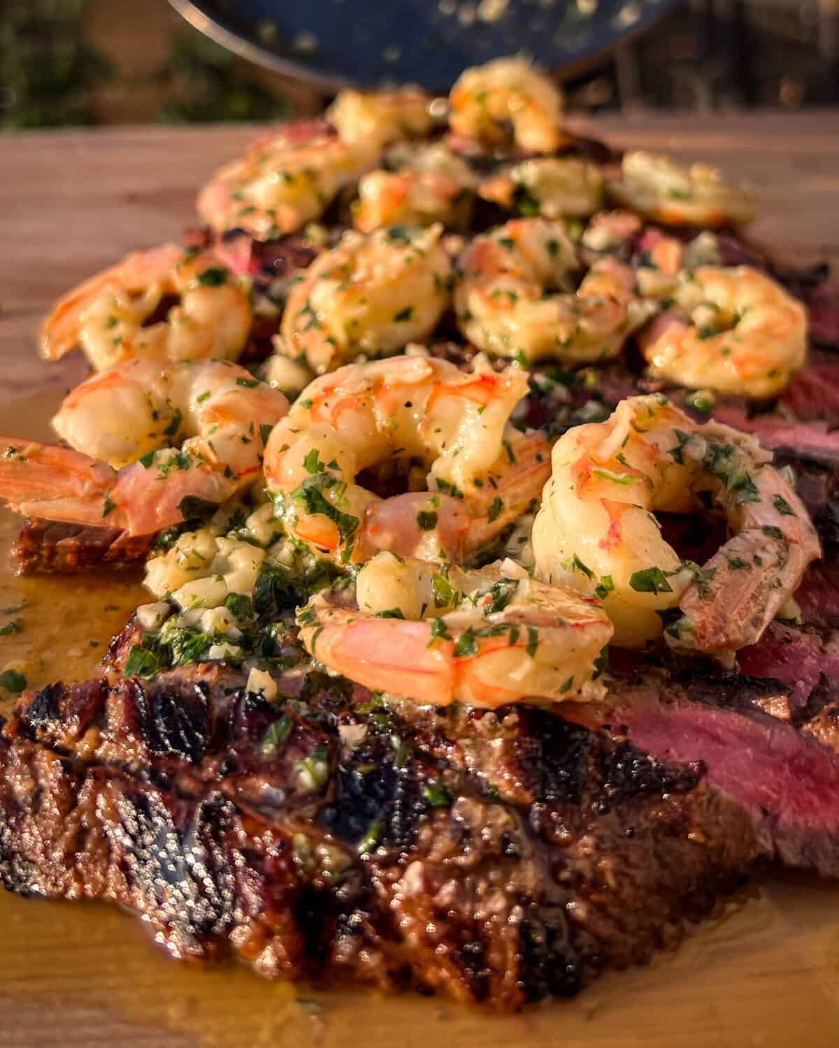 A grilled flank steak topped with garlic shrimp.