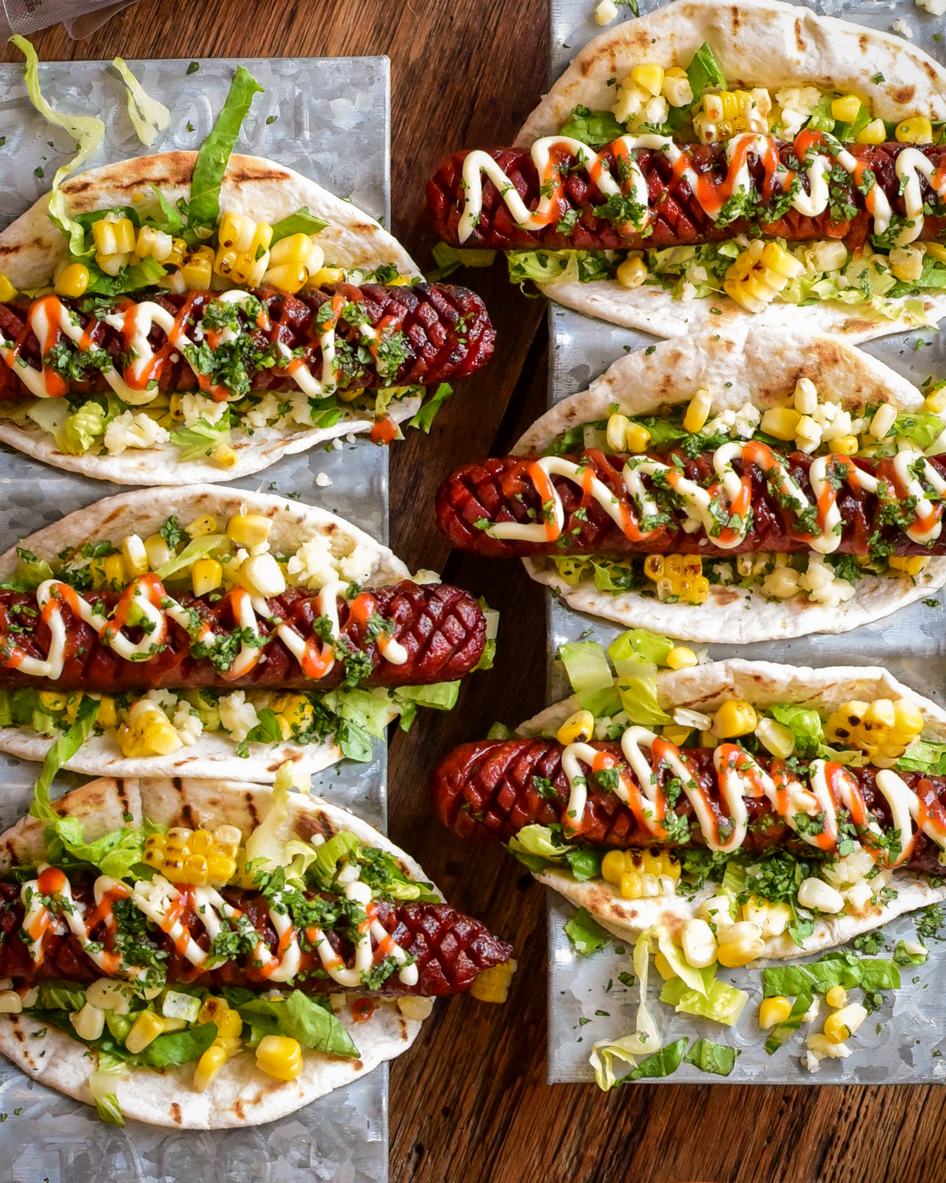 Six crosshatched beef smokies in taco holders dressed with Elote-style corn ingredients.