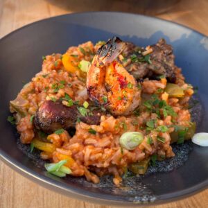 A bowl of grilled jambalaya with grilled shrimp, chicken and sausage.
