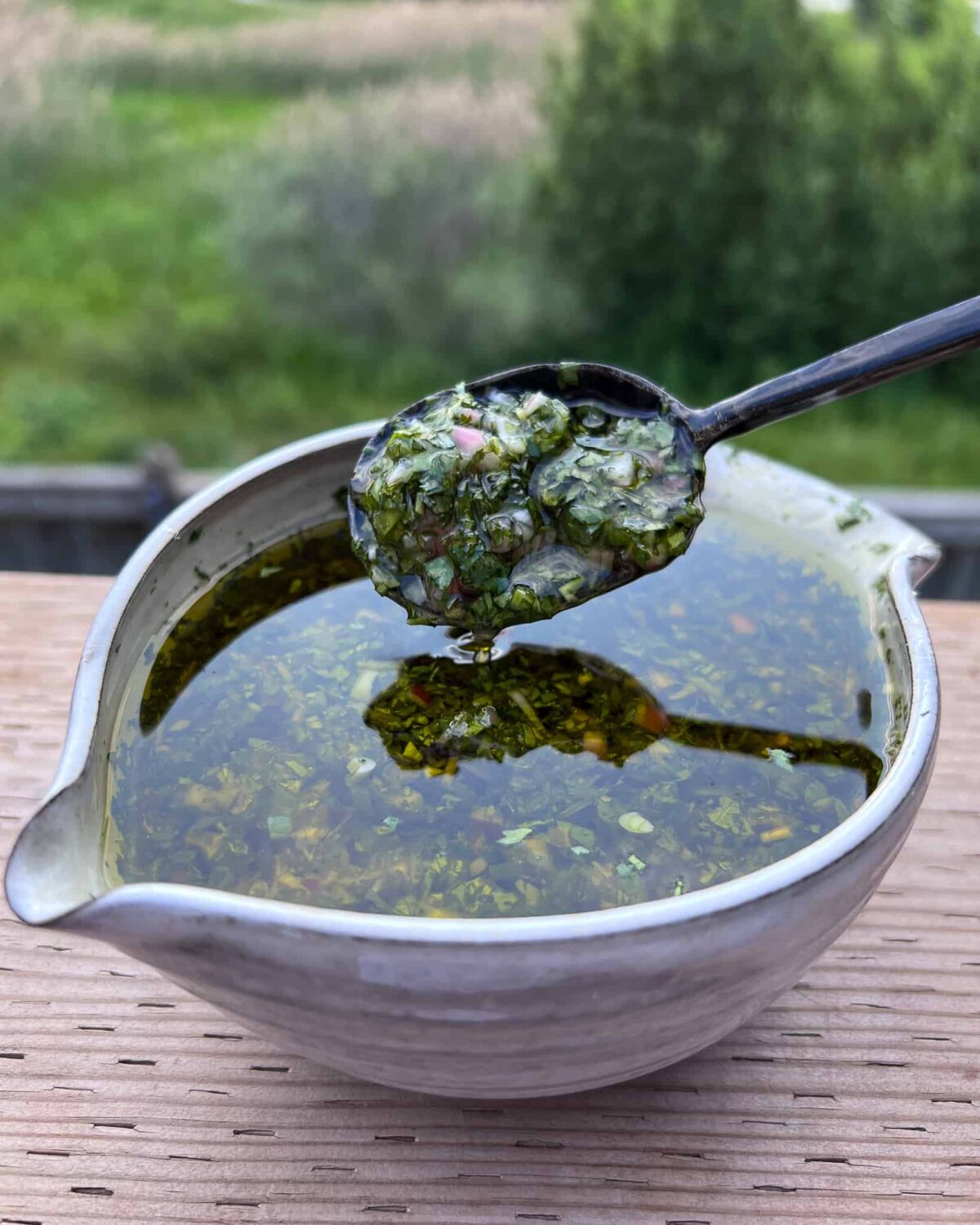 A bowl of herby steak sauce similar to a chimichurri.