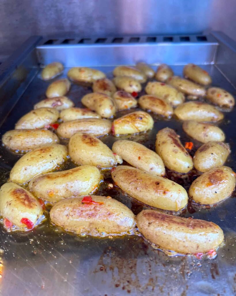 Potatoes cut side down on the griddle getting cooked in the steak drippings.