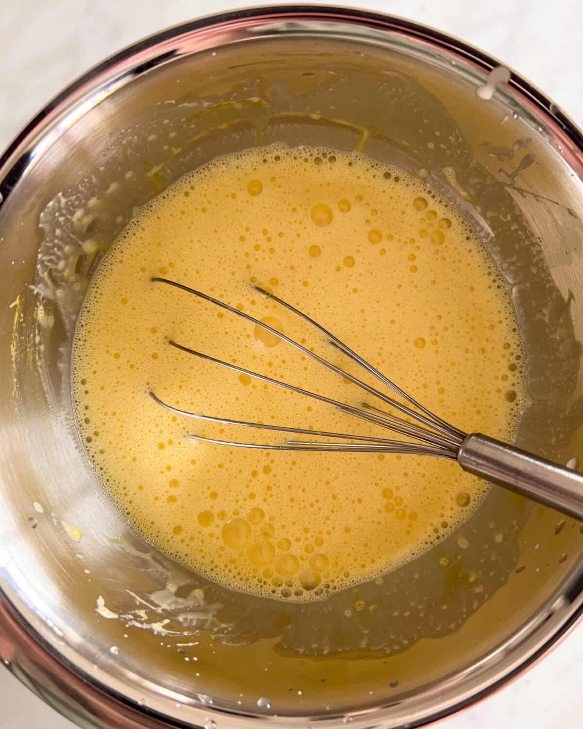 Slowly mix the warm cream mixture into the eggs.