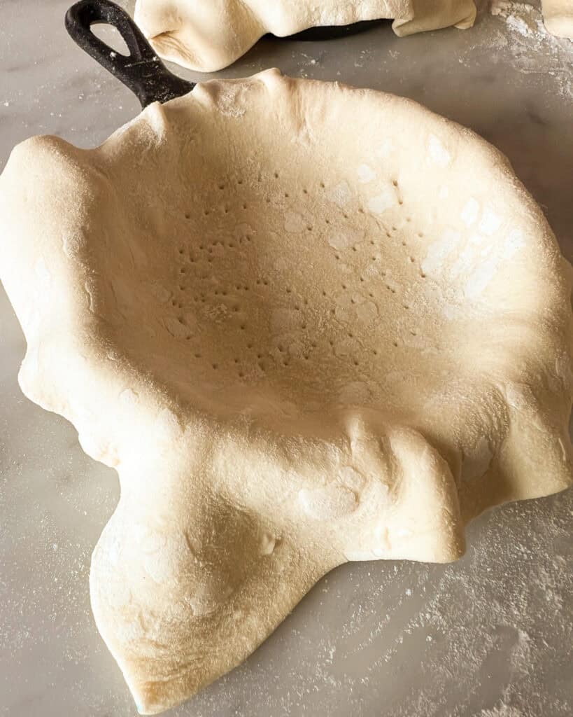 A draped square of puff pastry with the center pricked by a fork.