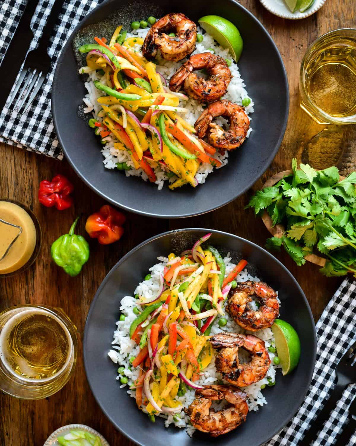Two bowls of jerk shrimp and rice with a peach-mango slaw.