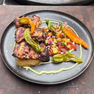 Grilled Piri Piri (peri peri) Chicken thighs served with a spicy peach salsa, fingerling potatoes, an avocado crema and smoky blistered shishito peppers.