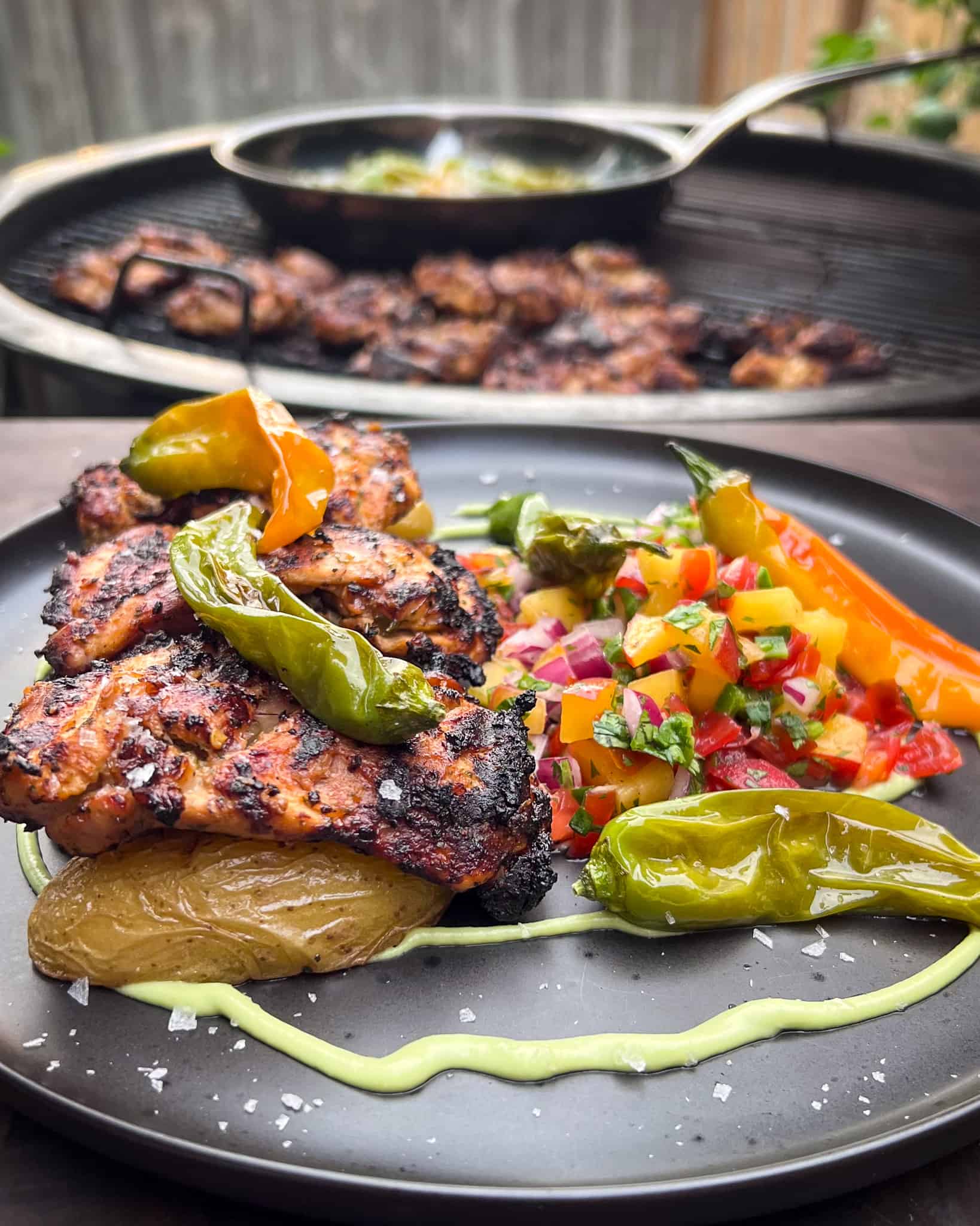 Grilled Piri Piri Chicken thighs served with a spicy peach salsa, fingerling potatoes, an avocado crema and smoky blistered shishito peppers.