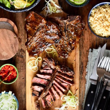 Three Teriyaki T-Bone Veal Chops on a cutting board and one is sliced.