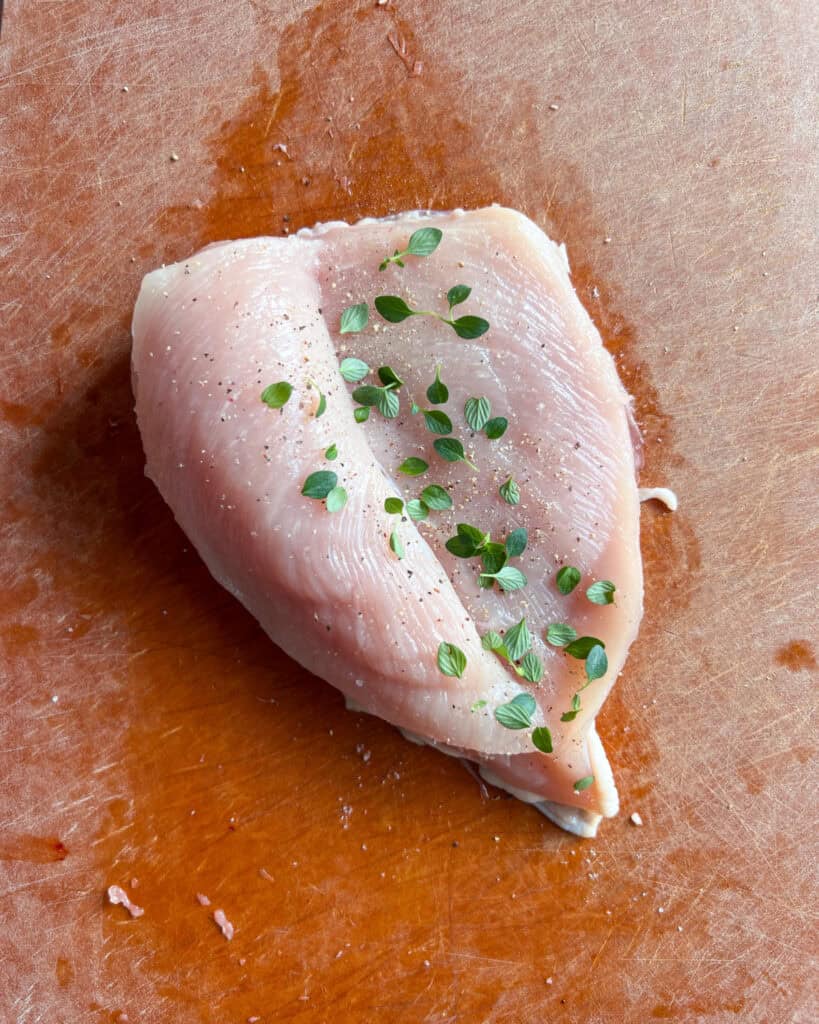 A butterflied chicken breast seasoned with salt, pepper and fresh thyme.