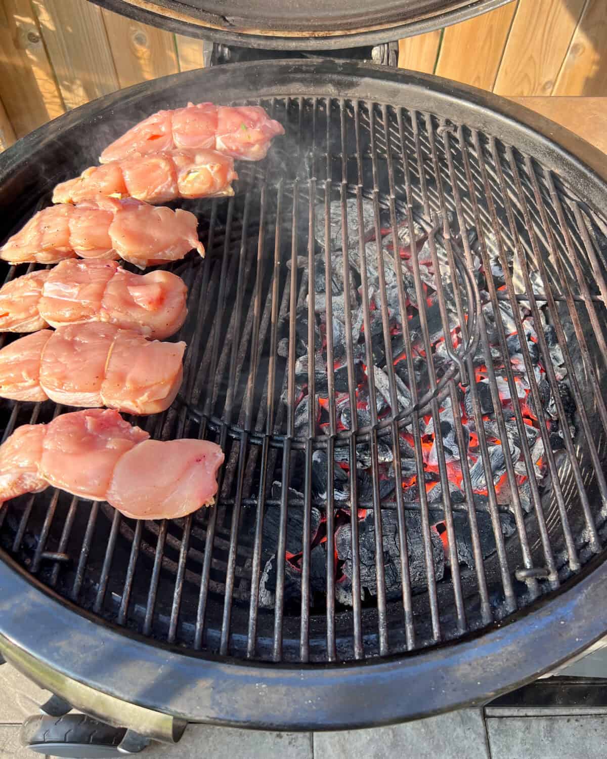 Chicken is placed on the indirect side of the grill, not over the hot coals.