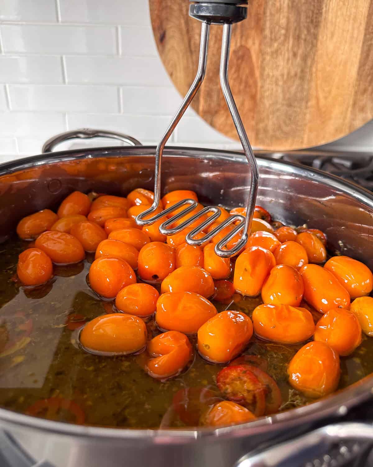 Use a potato masher to squish the tomatoes.