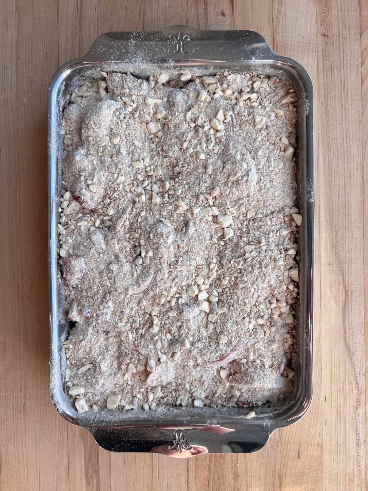 Crisp topping spread over peaches and strawberries ready to get baked.