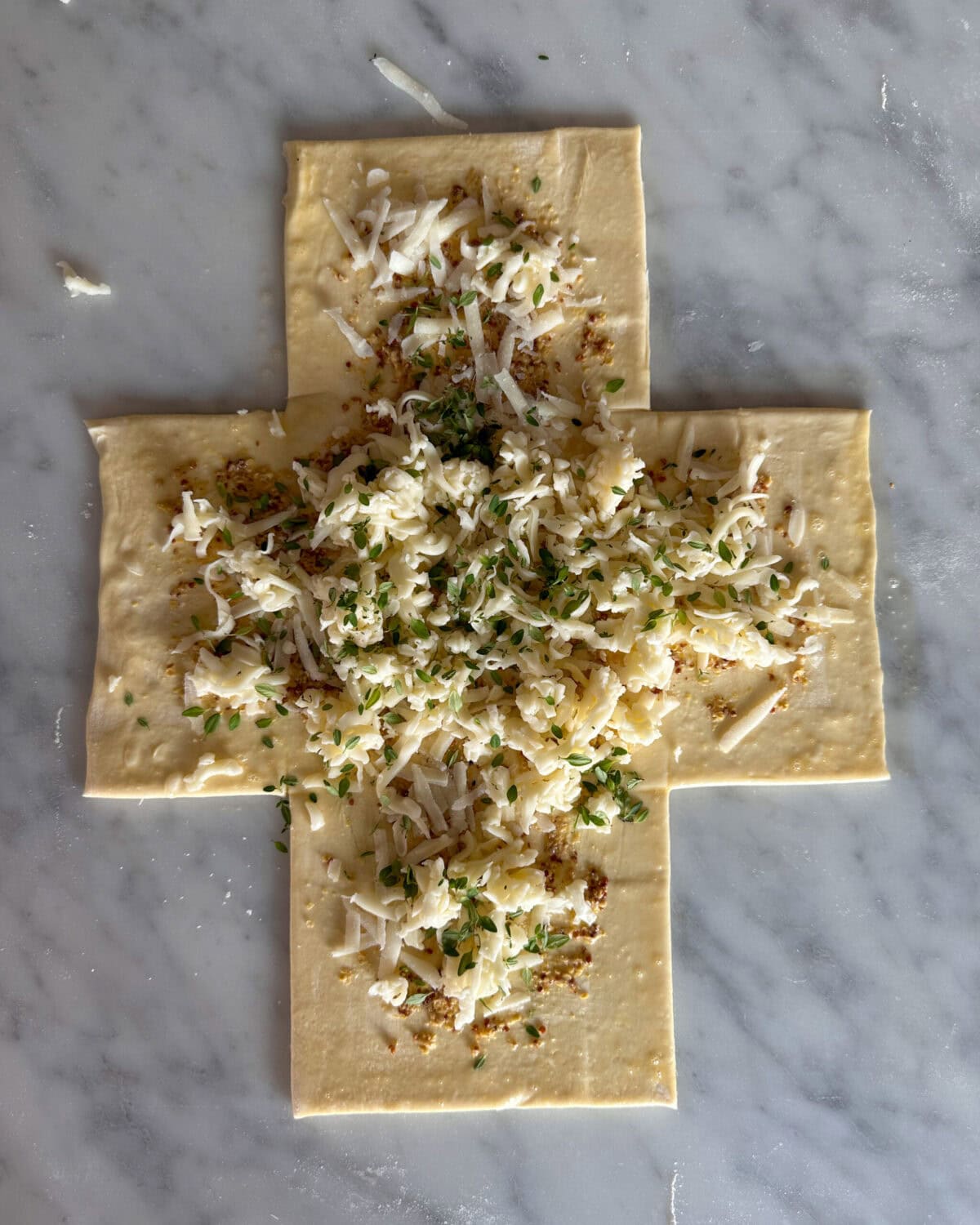 Spread the mustard on the inside of the pastry, within the egg wash border and sprinkle both the cheeses and thyme evenly over the mustard.