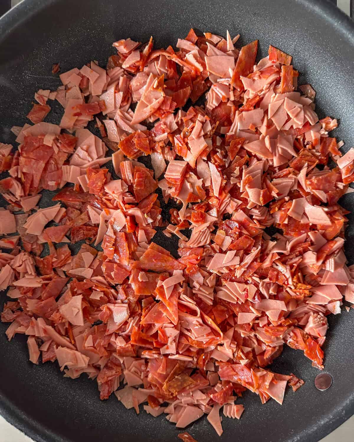 Warming the chopped deli meat in a pan.