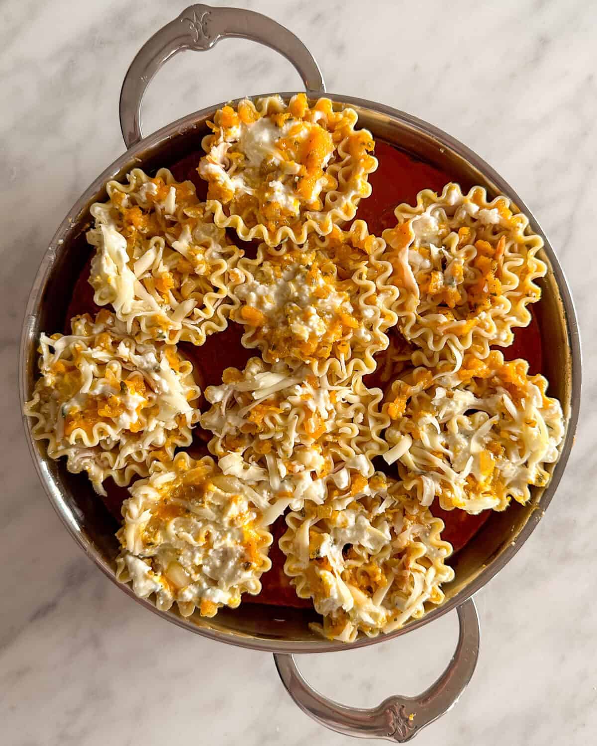 Nine roll ups nestled in a pan of tomato sauce.