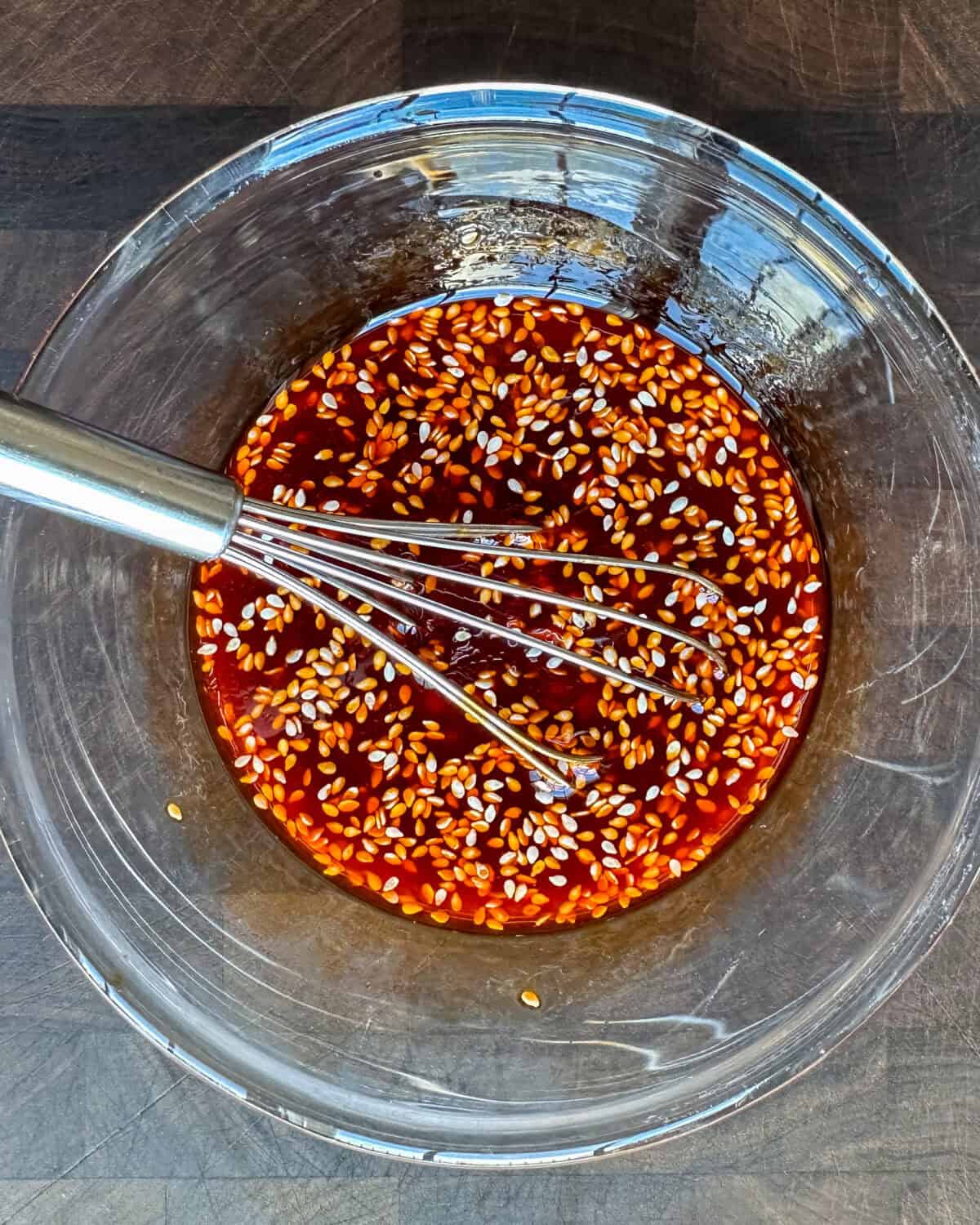 A bowl of wonton sauce with a whisk.