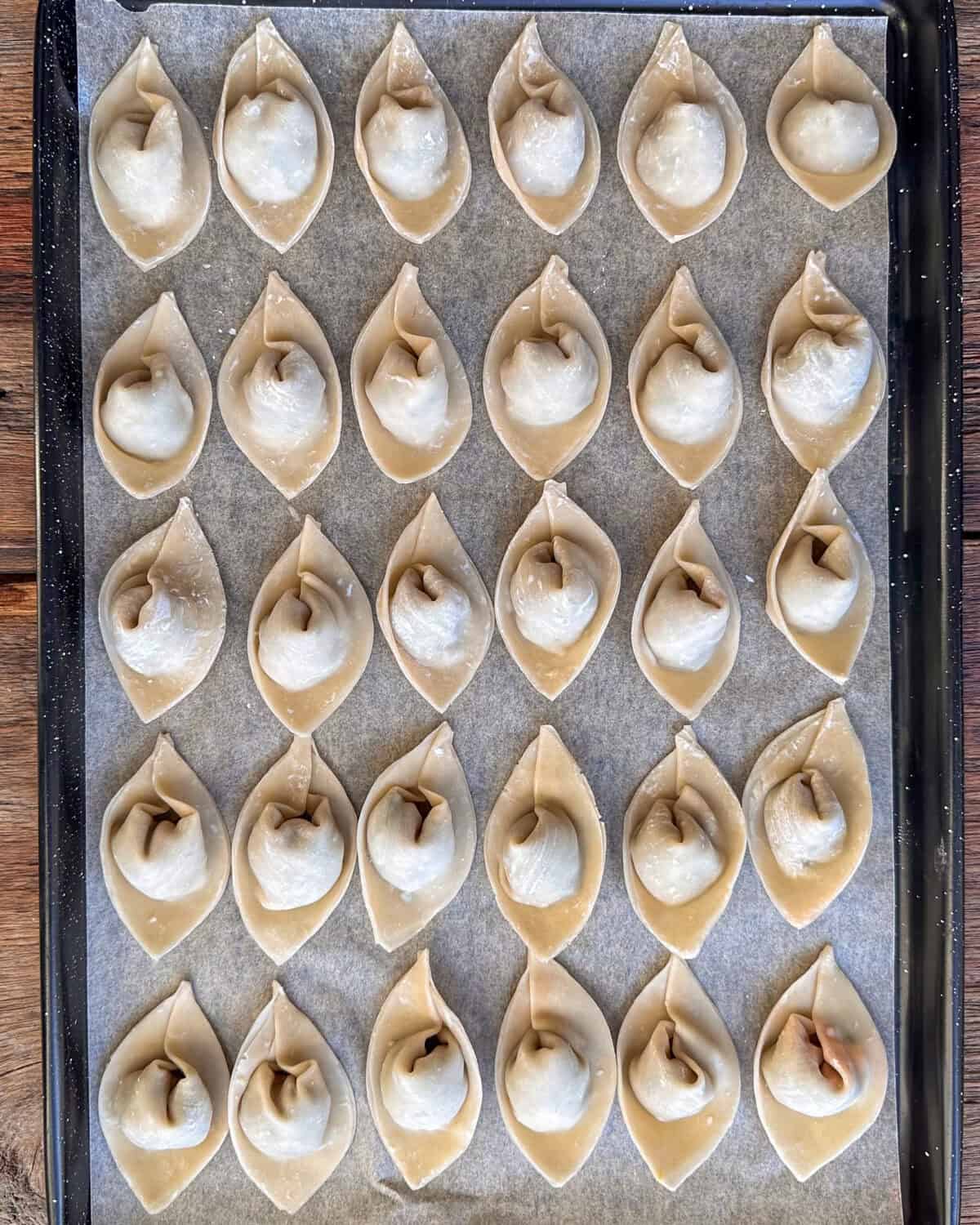 Wontons a sheet pan lined with parchment paper.
