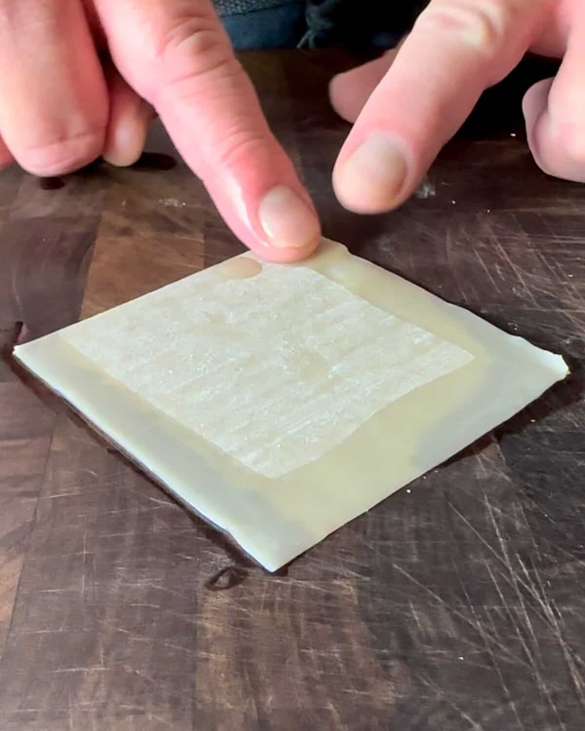 Dip your finger into a bowl of water.
Gently moisten all four edges of the wonton wrapper with the wet finger. This will help seal the wonton.