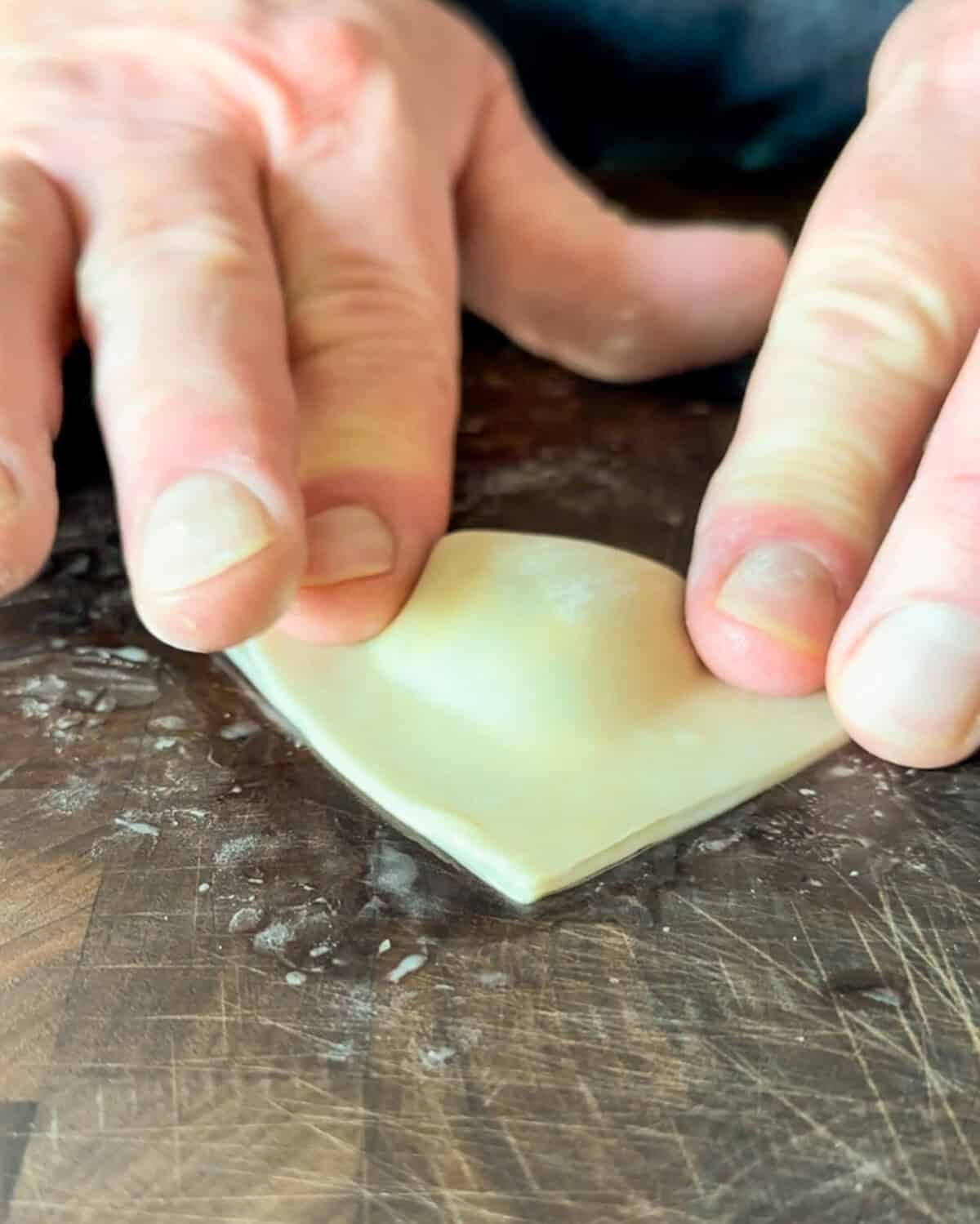 Fold the wonton wrapper diagonally to create a triangle shape. Press the edges to seal tightly, making sure there are no air pockets.