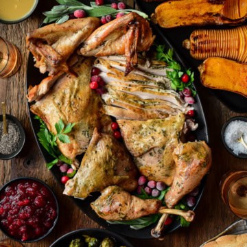 A carved Spatchcock Turkey with Herb Butter served with Jalapeno Ginger Cranberry sauce, gravy, grilled local sprouts on the stalk and hasselback butternut squash.