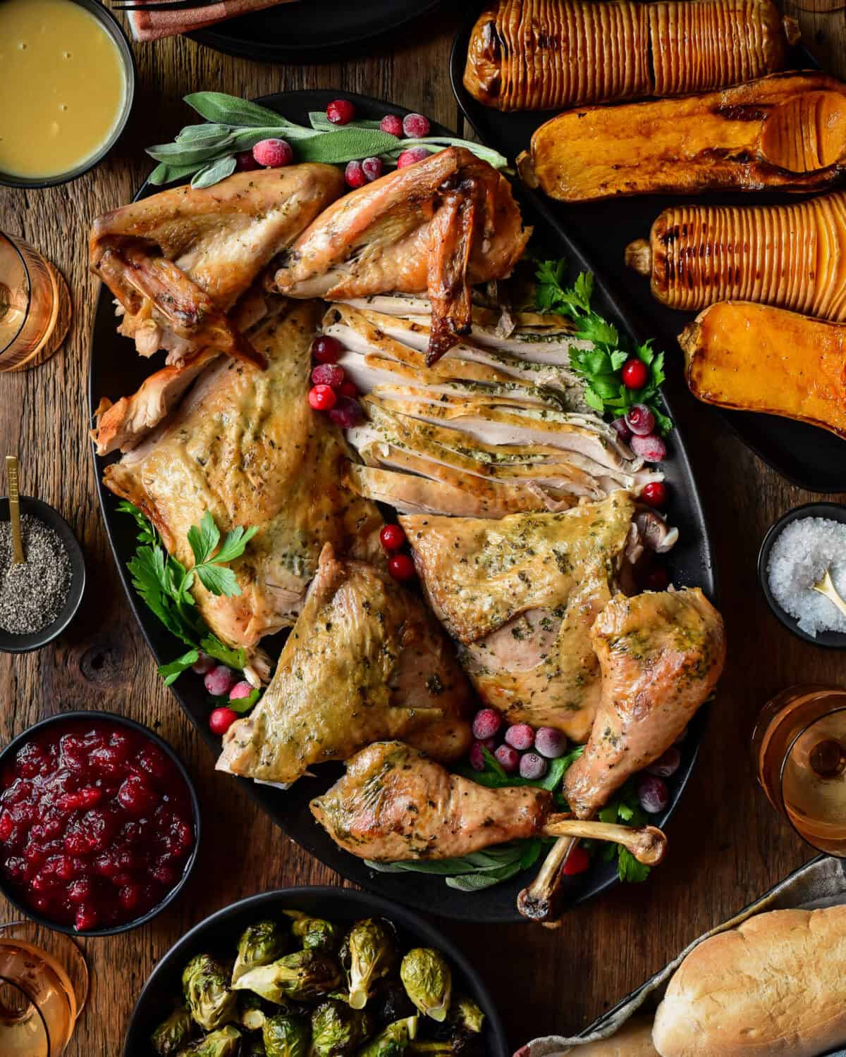 A carved Spatchcock Turkey with Herb Butter served with Jalapeno Ginger Cranberry sauce, gravy, grilled local sprouts on the stalk and hasselback butternut squash.