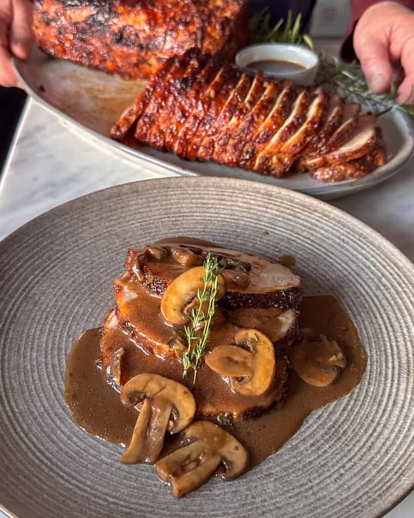 Serve pork loin roast with Marsala sauce and garnish with thyme.