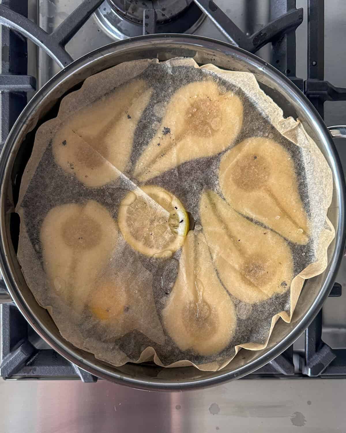 Add in the pears to the saucepan and cover with a round piece of parchment paper with a small hole cut in the center.