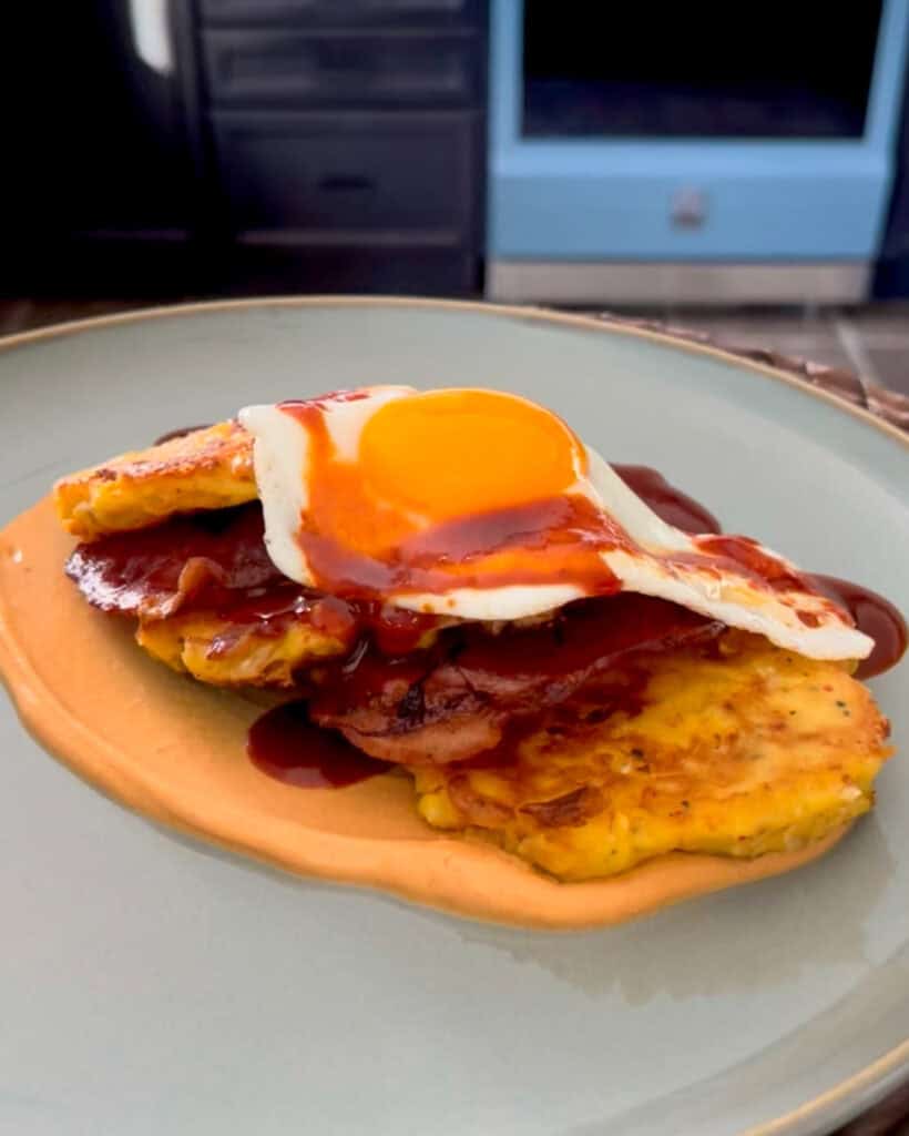Three kimchi potato pancakes layered with bacon and topped with a sunny side up egg.